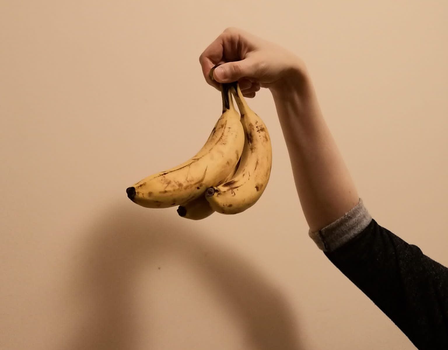 A member of Collective Futures holds up a small punch of three bananas.