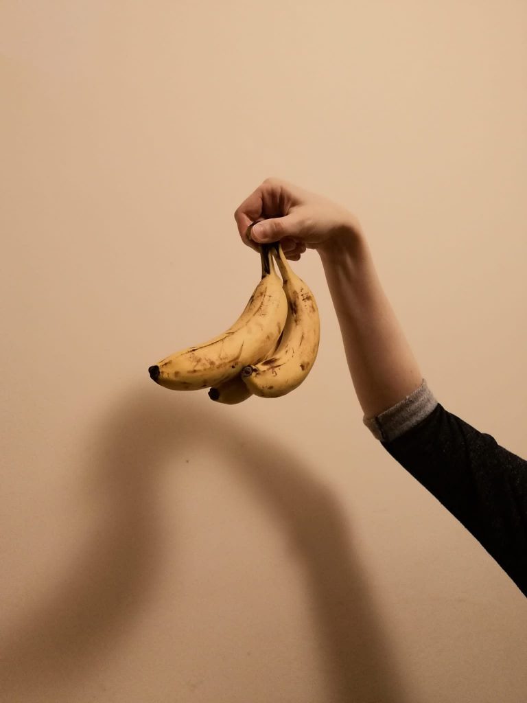 A member of Collective Futures holds up a small punch of three bananas.