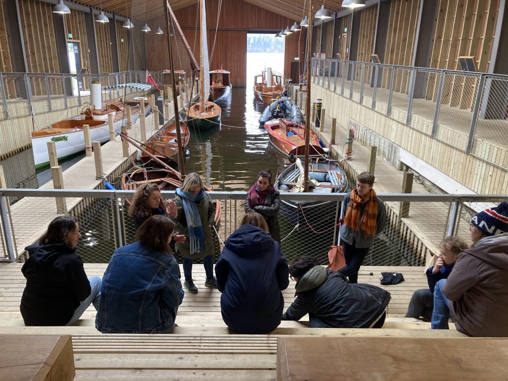 Members of Collective Futures gather in front of boats mored in a sheltered dock. 