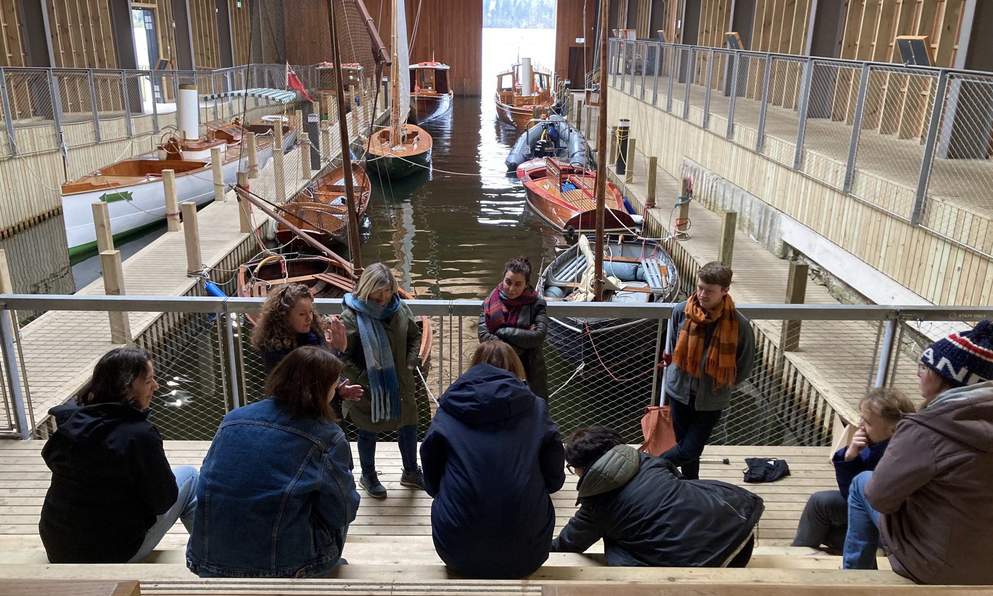 Members of Collective Futures gather in front of boats mored in a sheltered dock.